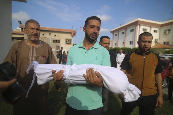 A relative carries the body of Amir Ganan, who was killed in an Israeli airstrike, during his funeral in Khan Younis, Gaza Strip, Tuesday, Oct. 10, 2023. (AP Photo/Hatem Ali)