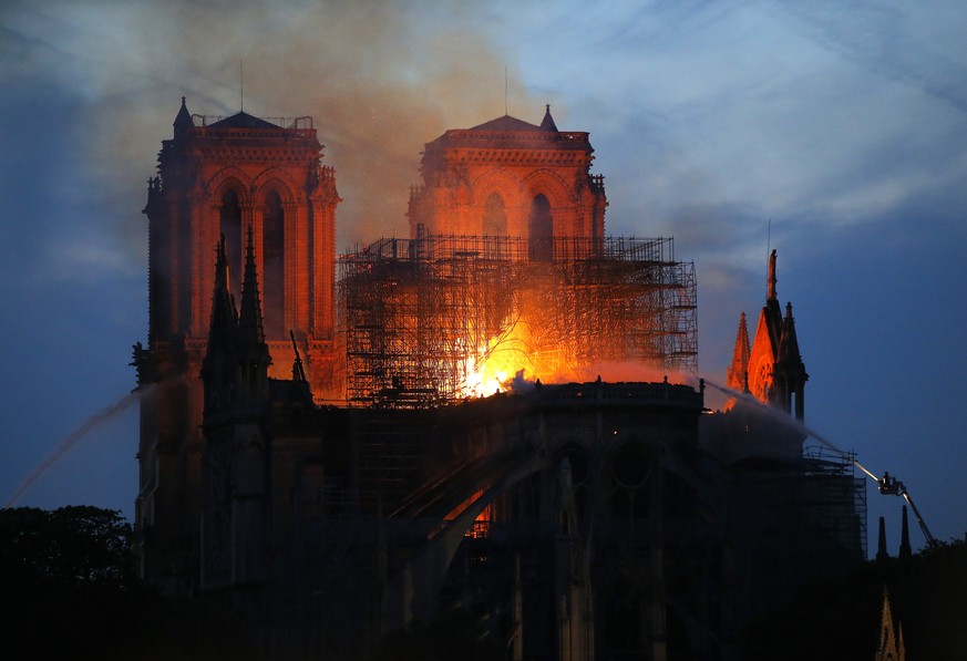 Firefighters tackle the blaze as flames and smoke rise from Notre Dame cathedral as it burns in Paris, Monday, April 15, 2019. Massive plumes of yellow brown smoke is filling the air above Notre Dame ...