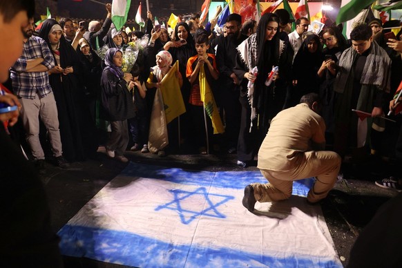 An Iranian man steps on the Israeli flag during a celebration, after the IRGC attack on Israel, in Tehran, Iran, October 1, 2024. Majid Asgaripour/WANA (West Asia News Agency) via REUTERS ATTENTION ED ...