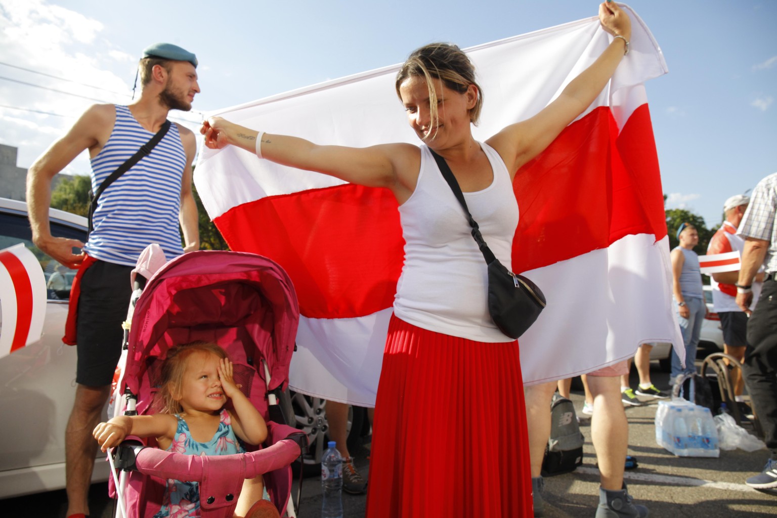 17.08.2020, Belarus, Minsk: Eine Frau hält bei einer Demonstration eine große historische Flagge von Belarus. Nach Tagen der Proteste in Belarus gegen Staatschef Lukaschenko wächst der Druck auf den M ...