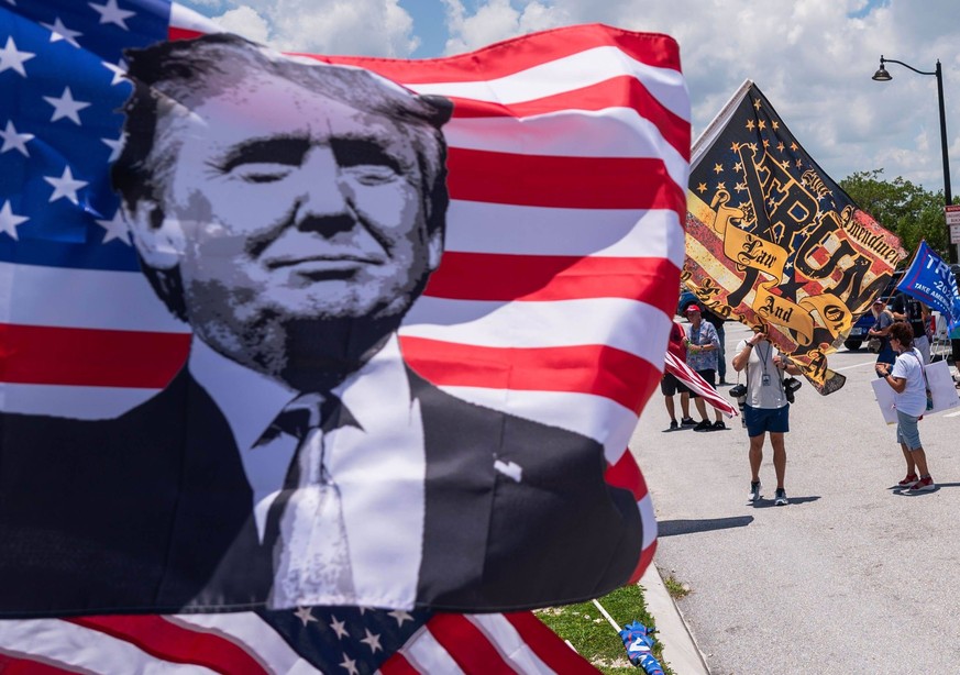 Syndication: Palm Beach Post A group of supporters of the former President Donald Trump waves flags at passing traffic during a pro-Trump event on Sunday, June 11, 2023, on the bridge portion of South ...