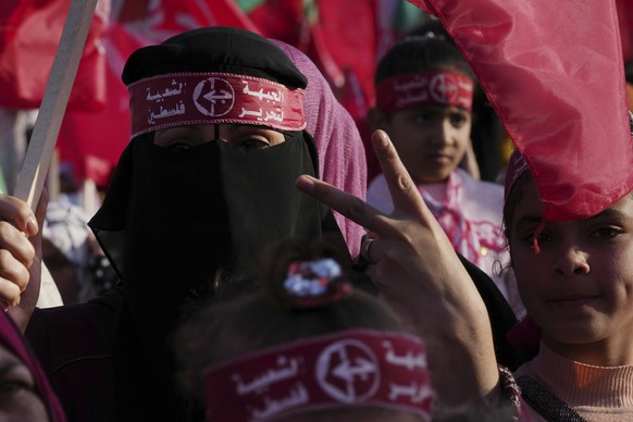 A veiled woman activist from the the Popular Front for the Liberation of Palestine (PFLP) waves her national and party&#039;s red flags while mark the 55th anniversary of the PFLP, at Al Kateba Square ...