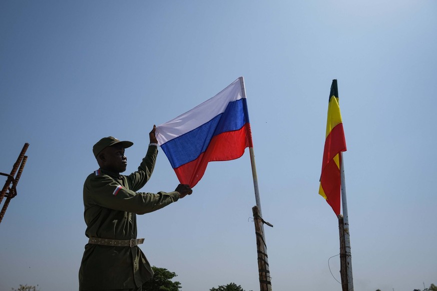 Aboubacar Kane, 49, climbed to the roof of his house in the Badalabougou neighborhood of Bamako on November 3, 2021, where he proudly poses in military garb holding the Russian flag next to an Ethiopi ...