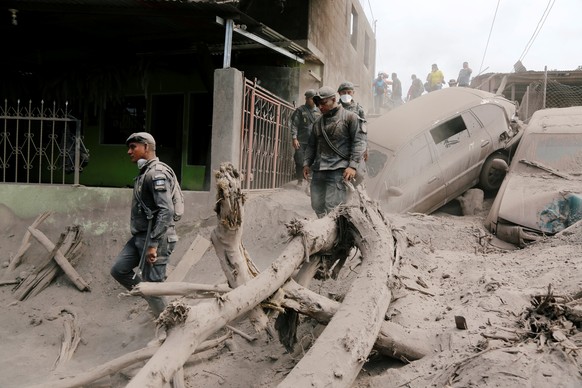 Policemen inspect at an area affected by the eruption of the Fuego volcano in the community of San Miguel Los Lotes in Escuintla, Guatemala June 5, 2018. REUTERS/Luis Echeverria