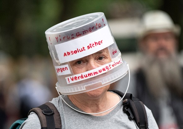 dpatopbilder - 01.08.2021, Berlin: Ein Demonstrant l�uft mit einem auf den Kopf gesetzten Plastikeimer, beschriftet mit &quot;Absolut sicher gegen das Verdummungsvirus&quot;, durch Berlin-Charlottenbu ...