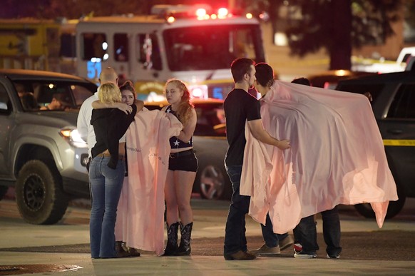 People comfort each other as they stand near the scene Thursday, Nov. 8, 2018, in Thousand Oaks, Calif. where a gunman opened fire Wednesday inside a country dance bar crowded with hundreds of people  ...