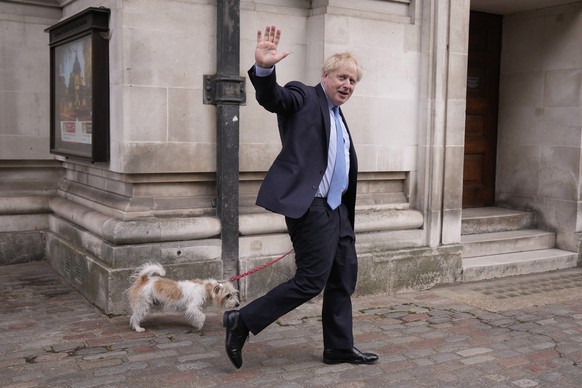 FILE - Britain's Prime Minister Boris Johnson waves at the media as he leaves with his dog Dilyn after voting at a polling station in London, for local council elections, Thursday, May 5, 2022. The mo ...