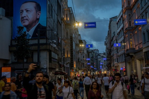 ISTANBUL, TURKEY - JUNE 18: People walk on Istanbul's famous Istiklal shopping street under a large election poster showing the portrait of Turkey's President Recep Tayyip Erdogan on June 19, 2018 in  ...