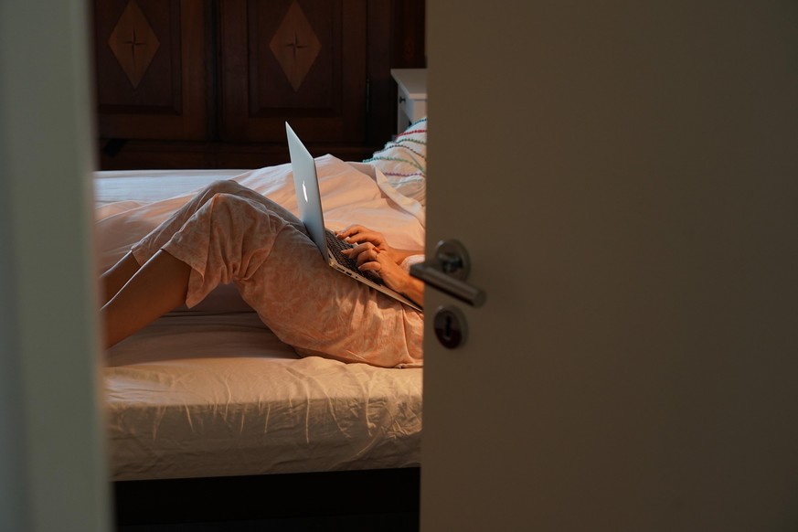 BERLIN, GERMANY - OCTOBER 29: Johana, the wife of the photographer, works on her laptop computer in their bed during her isolation for a Covid-19 infection on the 2nd day of his 14-day quarantine at h ...