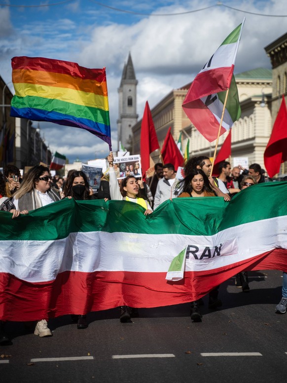 Protest für Mahsa Amini in München Teilnehmer*in mit Regenbogenflagge. Am 15. Oktober 2022, versammelten sich hunderte Teilnehmer*innen in München, um ihre Solidarität mit den Protestierenden im Iran  ...