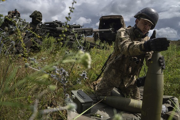 ARCHIV - 14.07.2022, Ukraine, Charkiw: Ein ukrainischer Soldat installiert einen Zünder für eine 155-mm-Artilleriegranate, bevor er mit einer von den USA gelieferten Haubitze des Typs M777 auf russisc ...