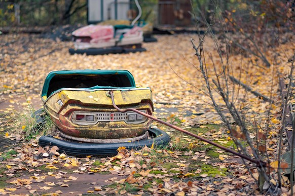 Wide shot of bumper cars in abandoned amusement park in Pripyat, Chernobyl Exclusion Zone in autumn