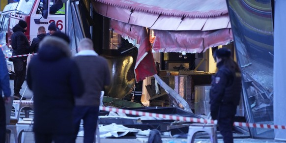 02.04.2023, Russland, St. Petersburg: Russische Ermittler und Polizisten stehen am Tatort nach einer Explosion in einem Cafe. Ein russischer Kriegsberichterstatter ist am Sonntag bei einer Explosion i ...