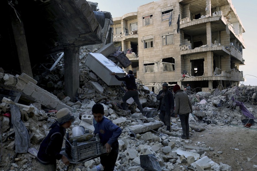 People remove furniture and household appliances out of a collapsed building after a devastating earthquake rocked Syria and Turkey in the town of Jinderis, Aleppo province, Syria, Tuesday, Feb. 7, 20 ...