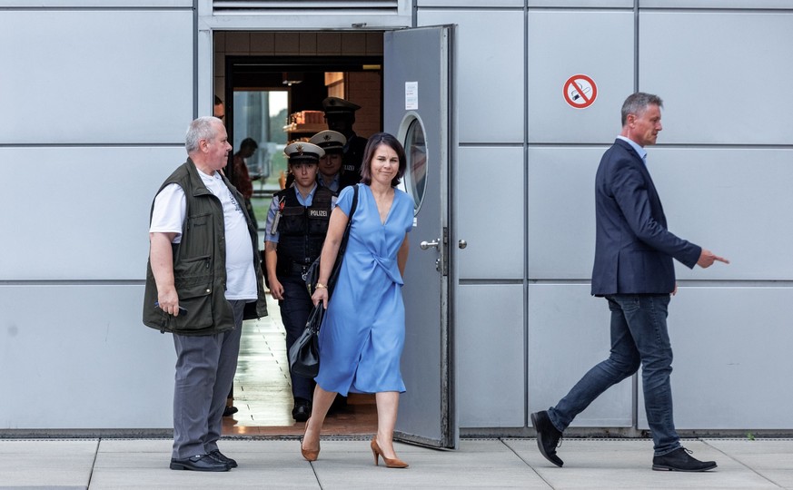 15.08.2023, Hamburg: Außenministerin Annalena Baerbock (Bündnis90/Grüne) geht nach ihrer Landung auf dem Flughafen Hamburg hinter einem Sicherheitsbeamten zu ihrem Fahrzeug. Nach den wiederholten Pann ...