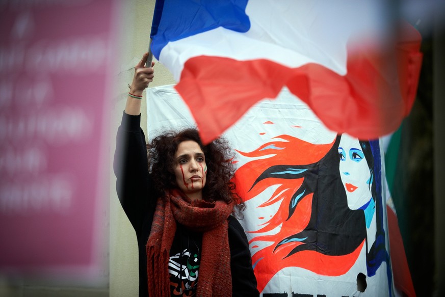 Protest For The Death Of Mahsa Amini And In Support Of Protesters In Iran A protester waves the French flag n ear a drawing depicting Mahsa Amini. Iranians of Toulouse organized a protest in Toulouse  ...