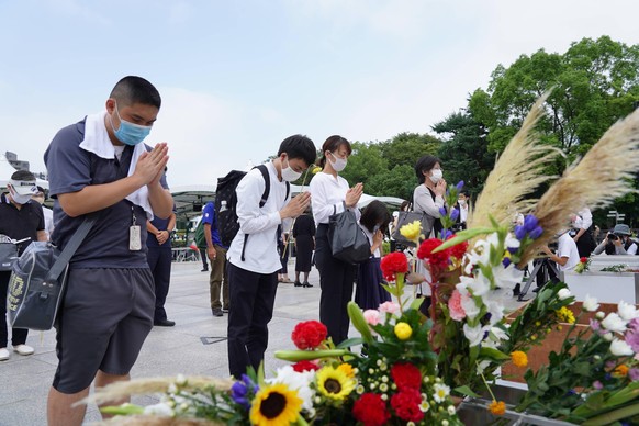 Teilnehmende legen bei der Gedenkstätte Blumen nieder.