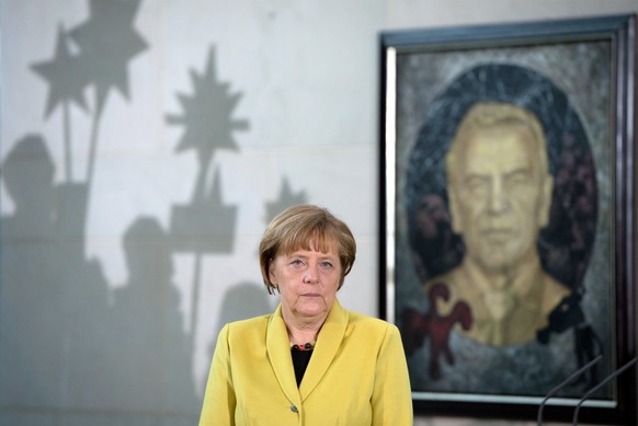 Angela Merkel im Kanzleramt. Von hinten grüßt das Schröderporträt.