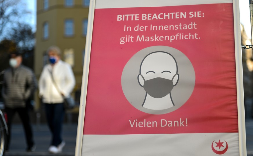 12.11.2020, Sachsen-Anhalt, Halle (Saale): &quot;Bitte beachten Sie: In der Innenstadt gilt Maskenpflicht.&quot; steht auf einem Plakat am Eingang zur Altstadt. Seit Monatsbeginn gilt in Deutschland e ...