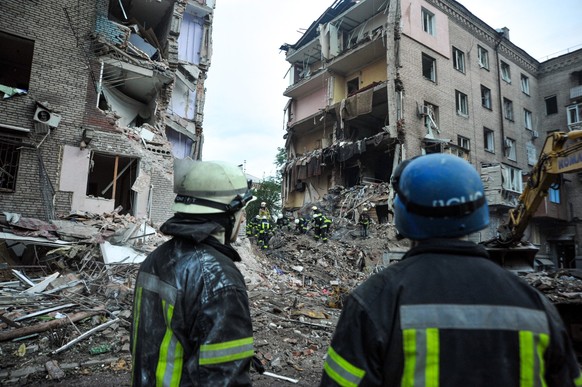 ARCHIV - 10.10.2022, Ukraine, Saporischschja: Rettungskr�fte schauen auf die Tr�mmer eines zerst�rten Wohnhauses. (zu dpa &quot;EU-Kommission will Russland zu Reparationszahlungen zwingen&quot;) Foto: ...