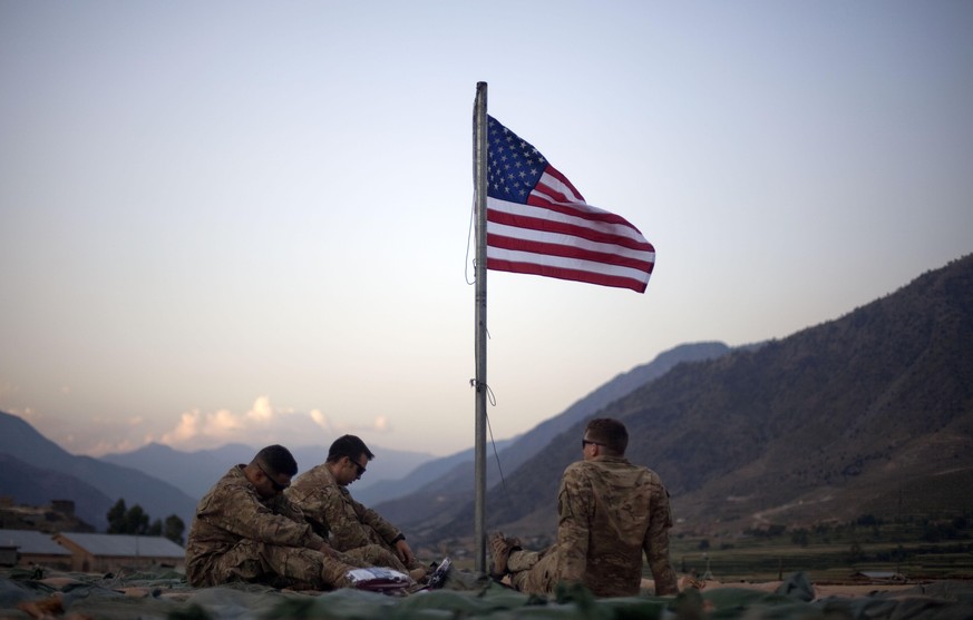 FILE - In this Sept. 11, 2011 file photo, US soldiers sit beneath an American flag just raised to commemorate the tenth anniversary of the 9/11 attacks at Forward Operating Base Bostick in Kunar provi ...