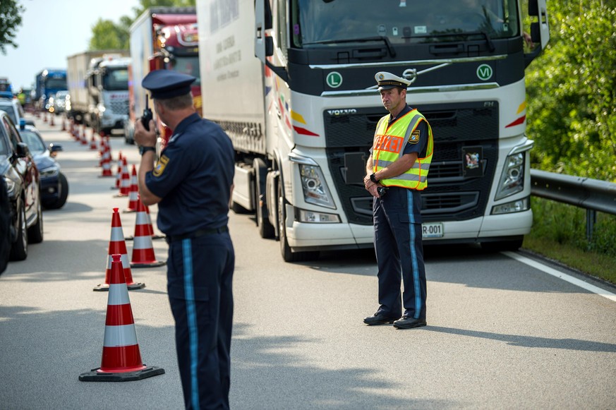 ARCHIV - 18.07.2018, Bayern, Kirchdorf: Ein Polizeibeamter stoppt zu Beginn der Grenzkontrollen durch die bayerische Landespolizei am Grenzübergang Kirchdorf den Verkehr. Foto: Lino Mirgeler/dpa +++ d ...