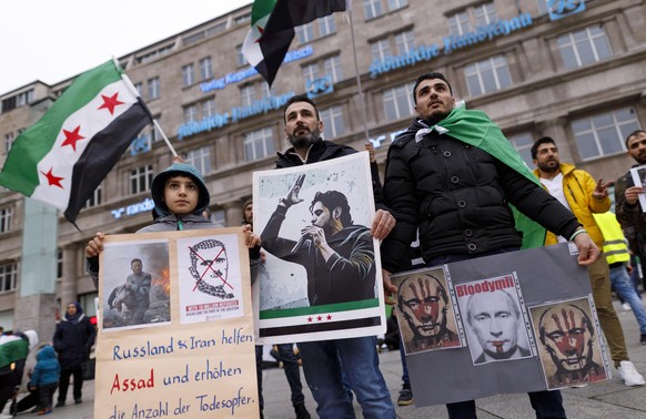 Demonstranten gegen Assad und Putin protestieren mit der Flagge der syrischen Revolution auf dem Bahnhofsvorplatz. Köln, 05.01.2020