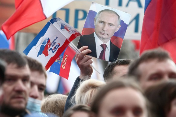 Krim, Feierlichkeiten am 7. Jahrestag der Krim-Annexion in Simferopol SIMFEROPOL, CRIMEA, RUSSIA - MARCH 18, 2021: A person holds a portrait of Russia s President Vladimir Putin during a concert in Le ...