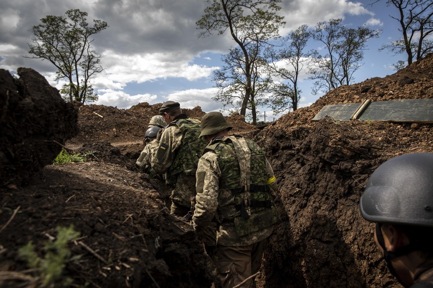 Ukrainische Soldaten gehen durch einen Schützengraben im Donbas.