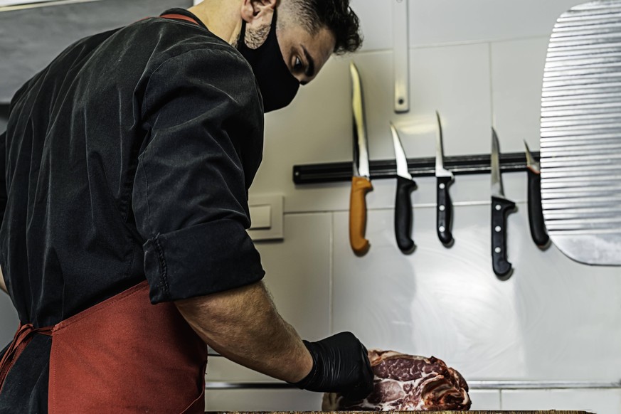 Butcher with mask cutting raw meat in the wood Novales, Cantabria, Spain PUBLICATIONxINxGERxSUIxAUTxONLY CR_JOAN200803-463119-01 ,model released, Symbolfoto ,property released