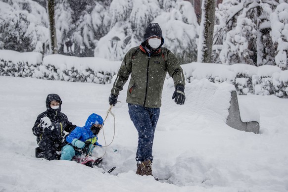 A man pushes his children on a sled during a heavy snowfall in Rivas Vaciamadrid, Spain, Saturday, Jan. 9, 2021. An unusual and persistent blizzard has blanketed large parts of Spain with snow, freezi ...