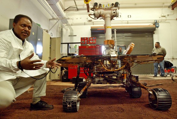 FILE - In this Feb. 4, 2004 file photo, Edward Tunstel Jr., left, a mobility engineer, briefs a reporter about the capability of the Mars rovers Spirit and Opportunity using this full-scale working ve ...
