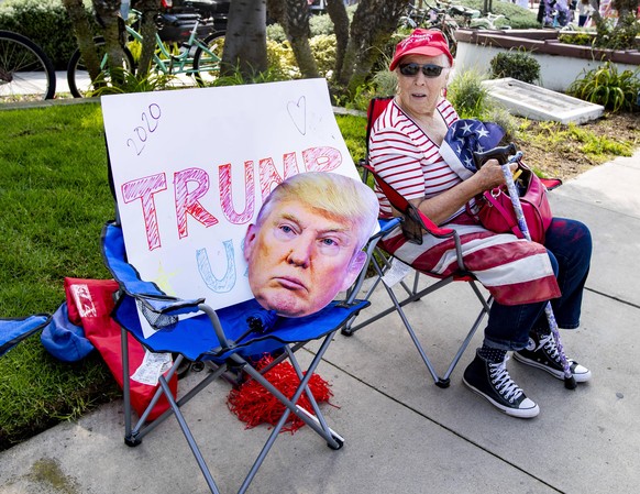 October 18, 2020, Newport Beach, California, USA: Elaine Reynolds, 82, of Garden Grove sits along Newport Boulevard hoping to get a glimpse Trump when his motorcade arrives in Newport Beach on Sunday, ...