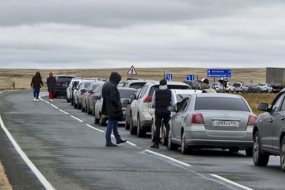 27.09.2022, Russland, Mariinsky: Menschen gehen neben ihren Autos in der Warteschlange f�r den Grenz�bertritt nach Kasachstan am Grenz�bergang Mariinsky. Zu Zehntausenden, wenn nicht zu Hunderttausend ...