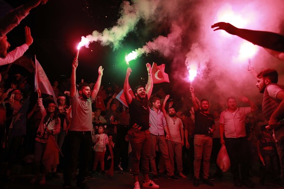 Supporters of Turkey's President and ruling Justice and Development Party, or AKP, leader Recep Tayyip Erdogan light flares celebrating outside the party headquarters in Istanbul, Sunday, June 24, 201 ...