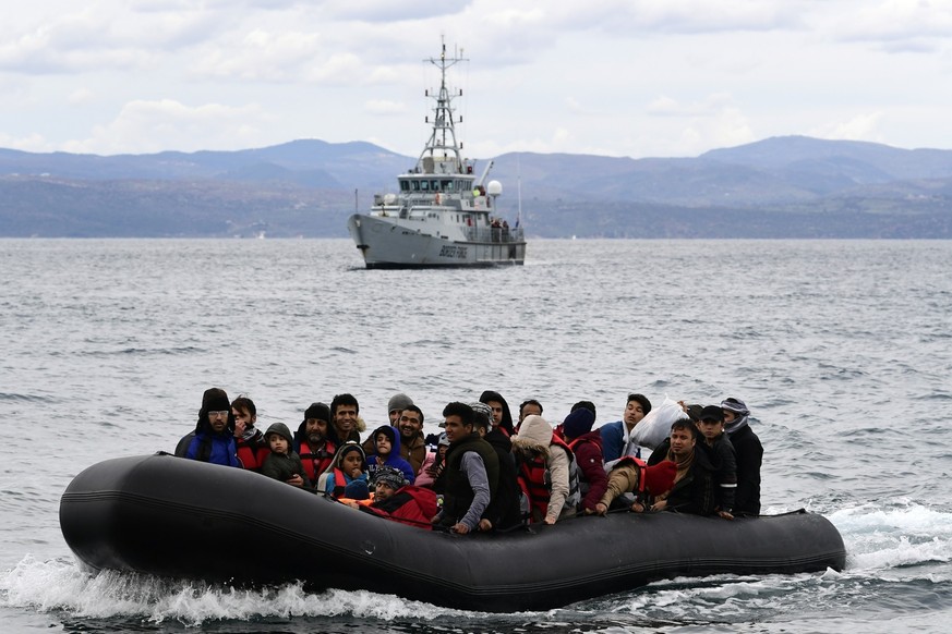 FILE - Migrants arrive with a dinghy accompanied by a Frontex vessel at the village of Skala Sikaminias, on the Greek island of Lesbos, after crossing the Aegean sea from Turkey, on Feb. 28, 2020. A m ...