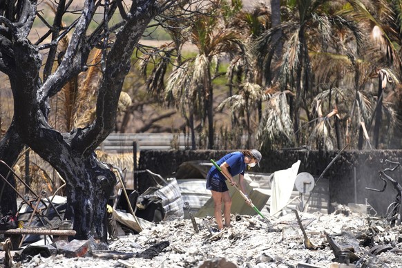 FILE - A woman digs through rubble of a home destroyed by a wildfire on Aug. 11, 2023, in Lahaina, Hawaii. With a housing crisis that has priced out many Native Hawaiians as well as families that have ...