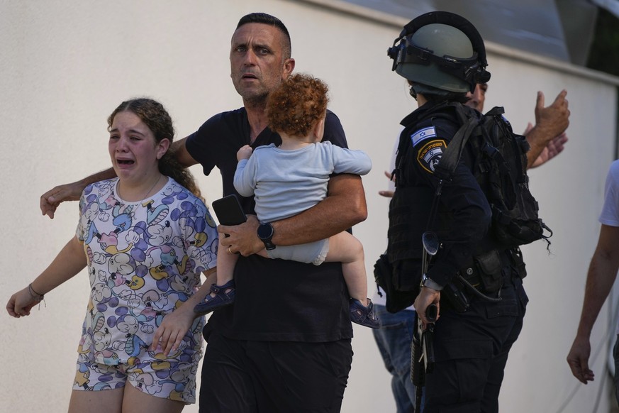 Israeli police officers evacuate a family from a site hit by a rocket fired from the Gaza Strip, in Ashkelon, southern Israel, Saturday, Oct. 7, 2023. The rockets were fired as Hamas announced a new o ...