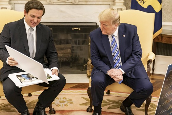 April 28, 2020, Washington, DC, United States of America: U.S. President Donald Trump, right, looks at diagrams and photos during his meeting with Florida Gov. Ron DeSantis in the Oval Office of the W ...