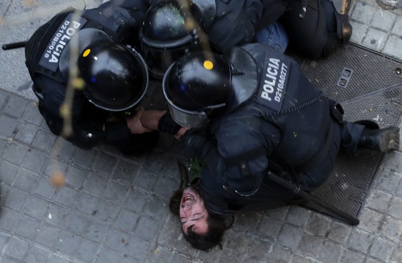 Catalan Mossos d'Esquadra regional police officers detain a man during clashes with pro-independence supporters trying to reach the Spanish government office in Barcelona, Spain, Sunday, March 25, 201 ...