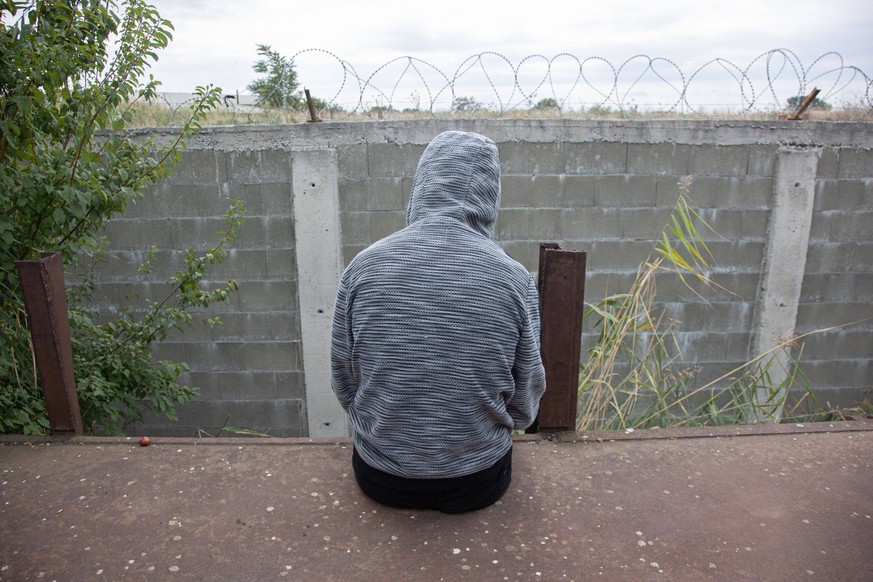 Refugee - Migrant Crisis In Greece Afghan refugee who waiting for next train, sitting on a carriage in front of the barbed wire. Refugees and migrants are seen at the railway junction and the old aban ...