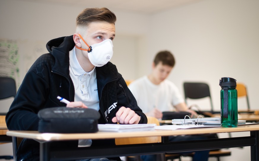 23.04.2020, Nordrhein-Westfalen, Übach-Palenberg: Zwei Schüler, einer davon mit einer Schutzmaske, bearbeiten Informatikaufgaben im Informatik-Grundkurs des Abiturjahrgangs am Carolus-Magnus-Gymnasium ...