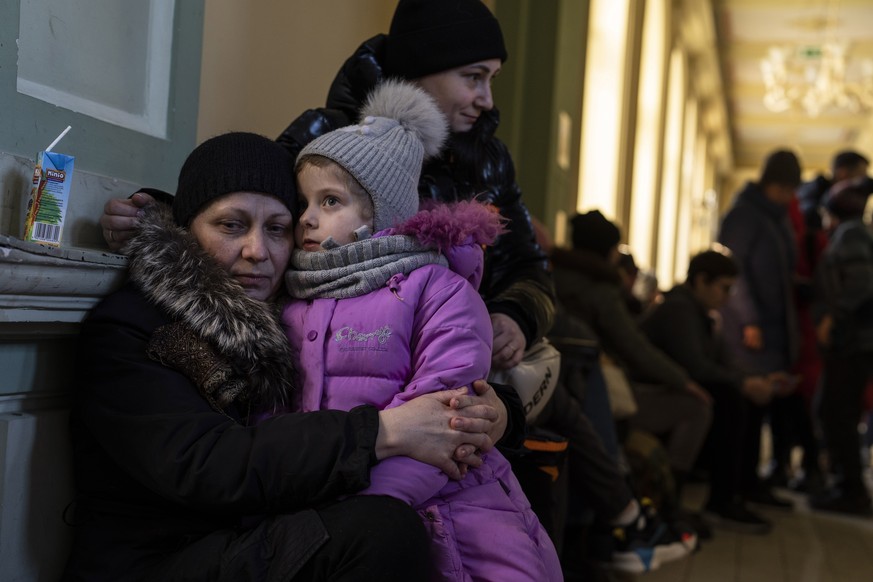 FILE - Ukrainian refugee Elena, left, hugs her five-year old granddaughter Christina, as they wait the train to Warsaw, at the Przemysl train station, southeastern Poland, on Friday, March 11, 2022. M ...