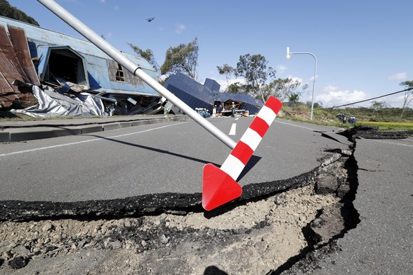 A cracked road and destroyed buildings are seen after an earthquake in Atsuma town, Hokkaido, northern Japan, Thursday, Sept. 6, 2018. Several people were reported missing in the nearby the town, wher ...