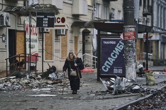 17.12.2022, Ukraine, Bachmut: Eine �ltere Anwohnerin geht mit ihren Gehstock eintlang besch�digter Geb�ude. Foto: Libkos/AP/dpa +++ dpa-Bildfunk +++