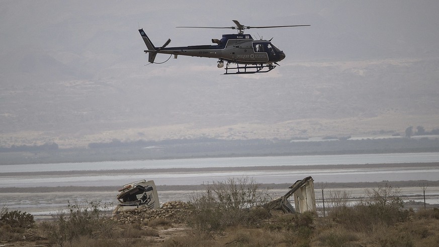 Israeli police helicopter searches the area above a truck that was swept in flood near Tzin river by the Dead Sea, Israel, Friday, April 27, 2018. Flash floods killed ten Israeli teenagers who were hi ...
