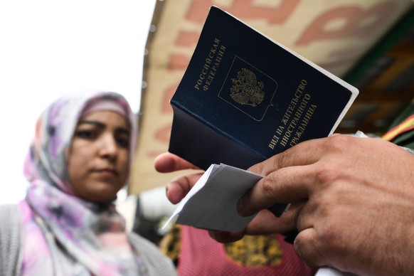 Russia Migrants 8742799 13.08.2024 A police officer checks the documents of market workers during a joint raid by the local investigative committee, police, national guard and military conscription of ...