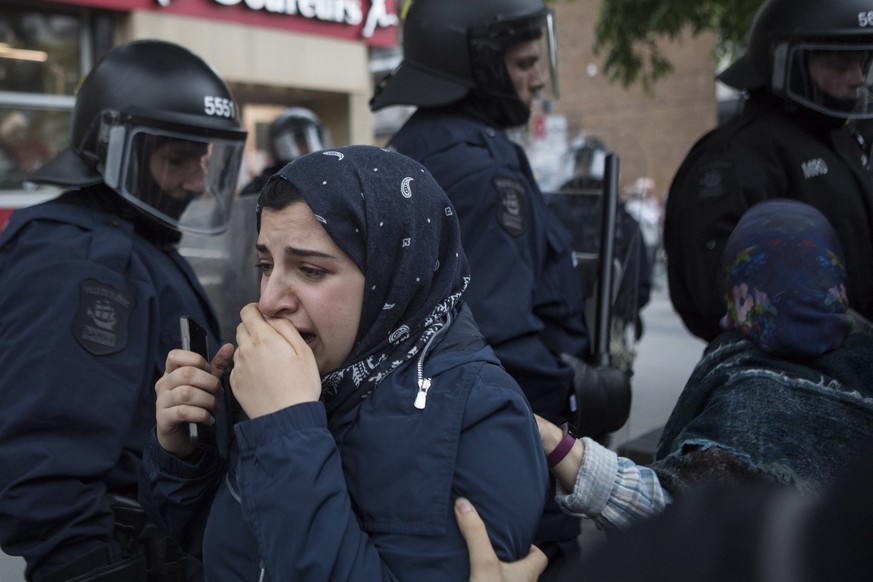 A passerby is helped past a line of police officers during an anti-G7 demonstration in Quebec City on Thursday, June 7, 2018, ahead of the G7 Summit. (Chris Young/The Canadian Press via AP)