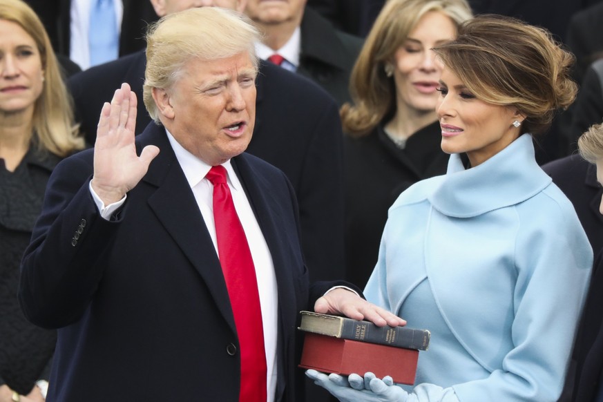 ARCHIV - 20.01.2017, USA, Washington: Donald Trump legt neben Ehefrau Melania, die die Bibel in den H