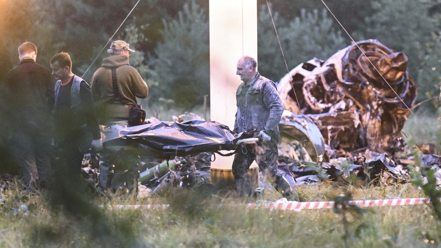 24.08.2023, Russland, Kushenkino: Menschen tragen einen Leichensack aus dem Wrack eines abgestürzten Privatjets in der Nähe des Dorfes Kuschenkino in der Region Twer. Der russische Söldnerführer Jewge ...